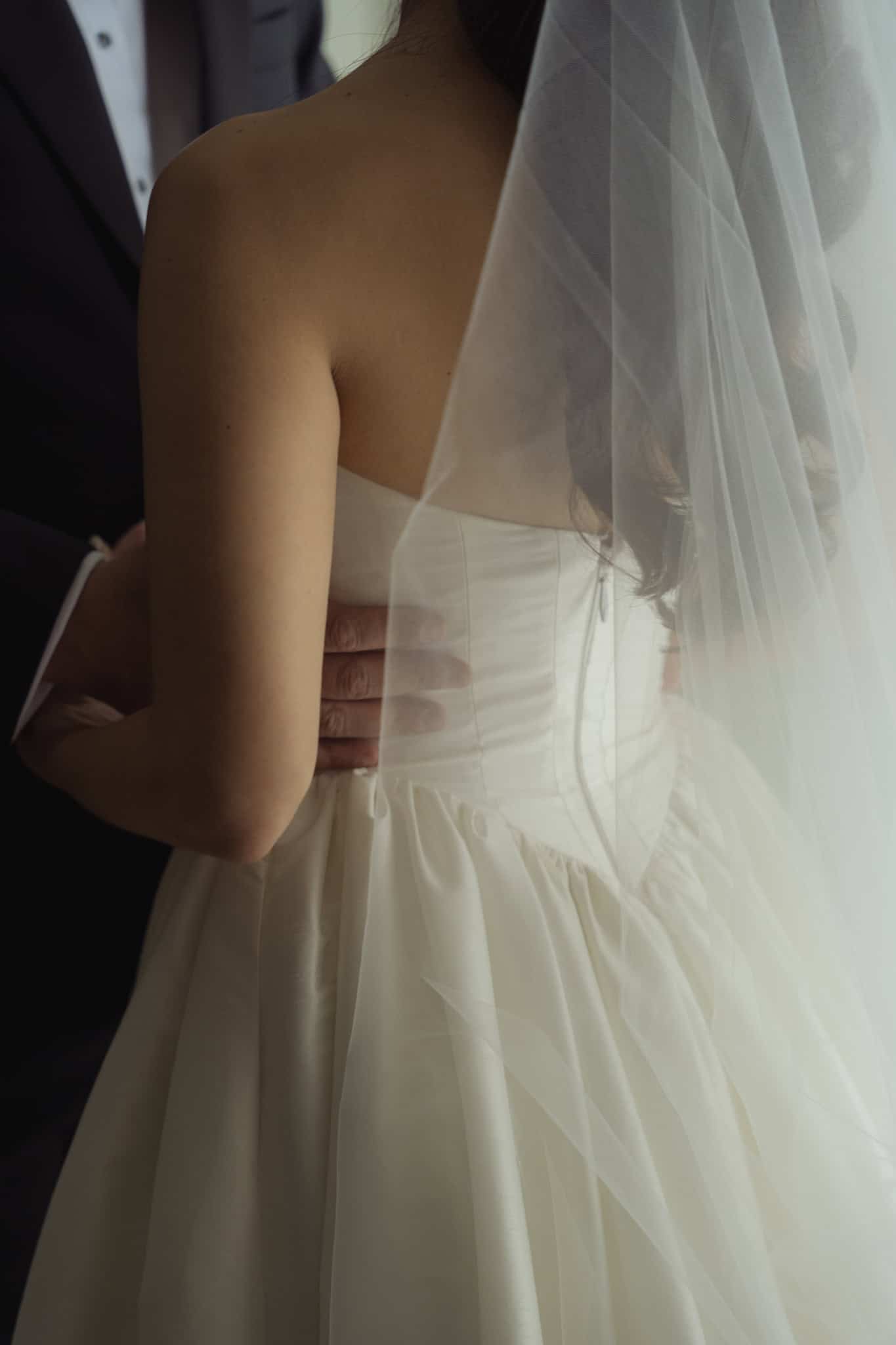 Close detail of a bride's gown and veil in low, warm light