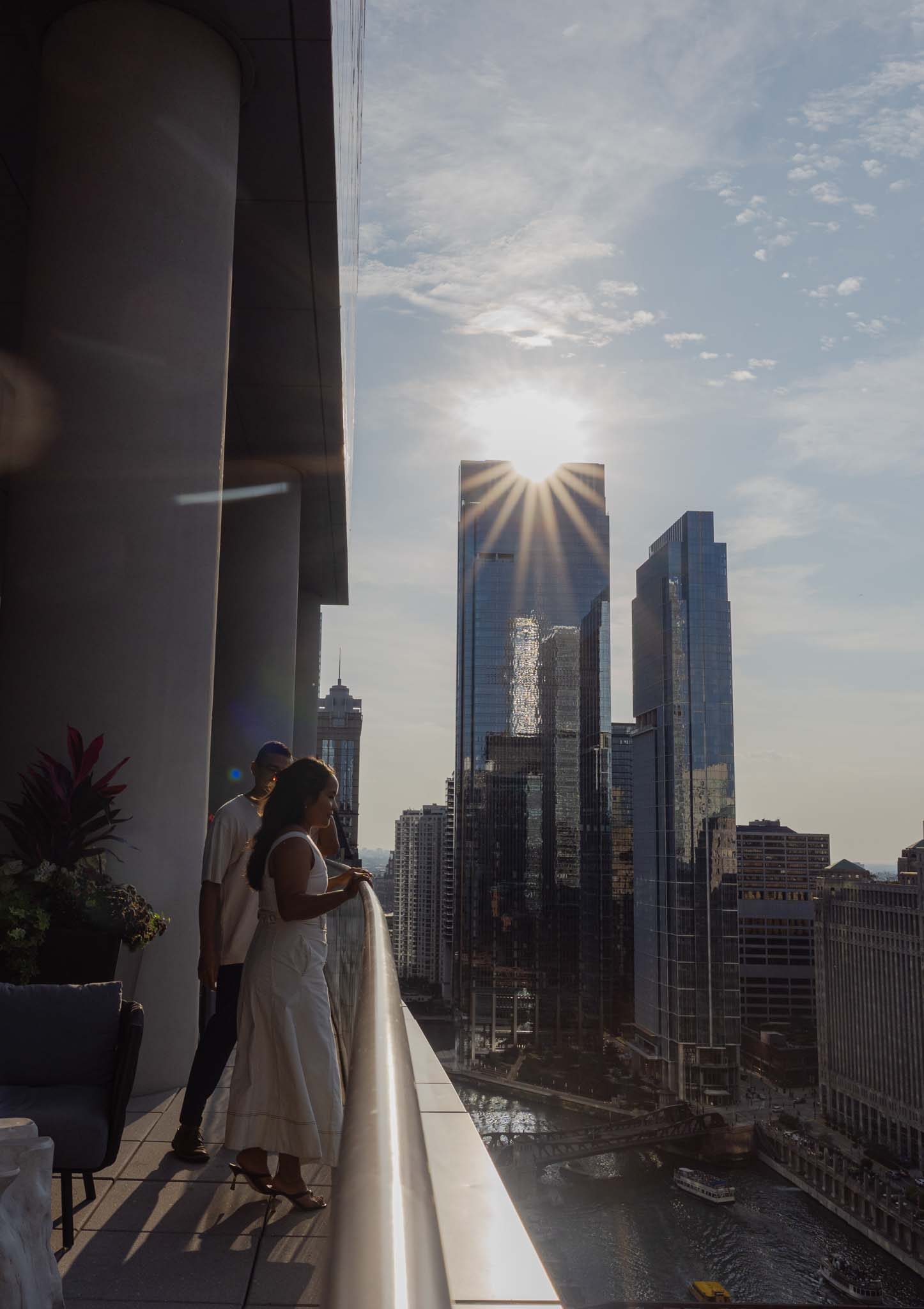 Alexis and Jason at the balcony rail, downtown Chicago towers and the river below