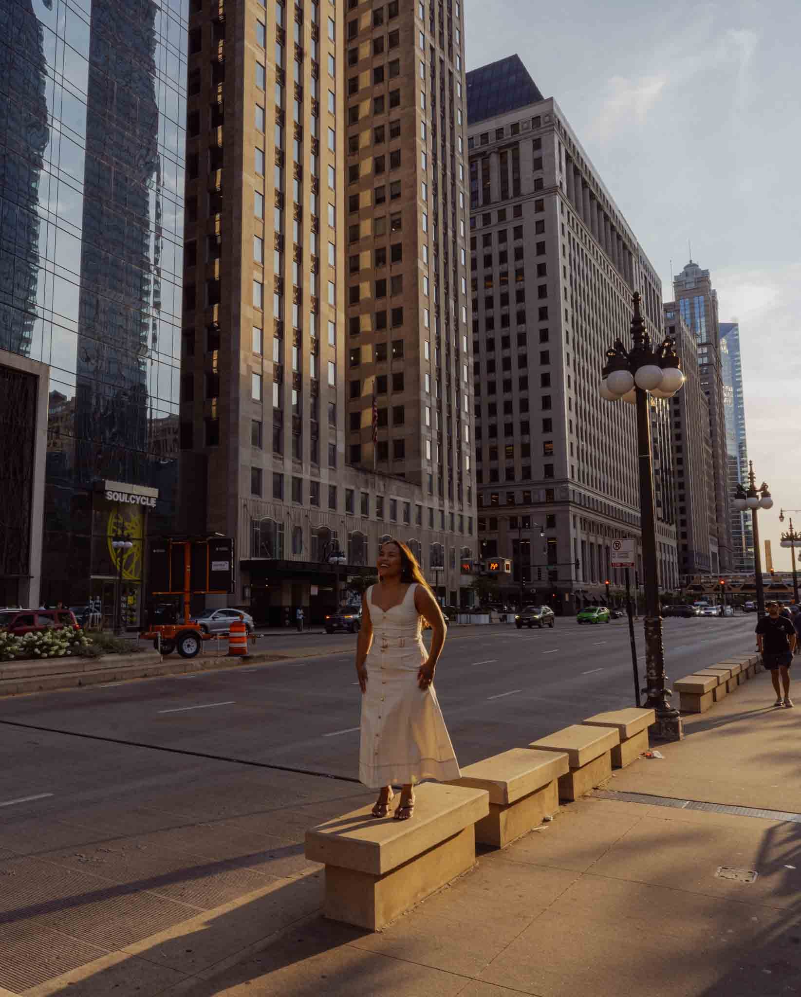 Alexis standing on a stone ledge along Wacker Drive in golden evening light