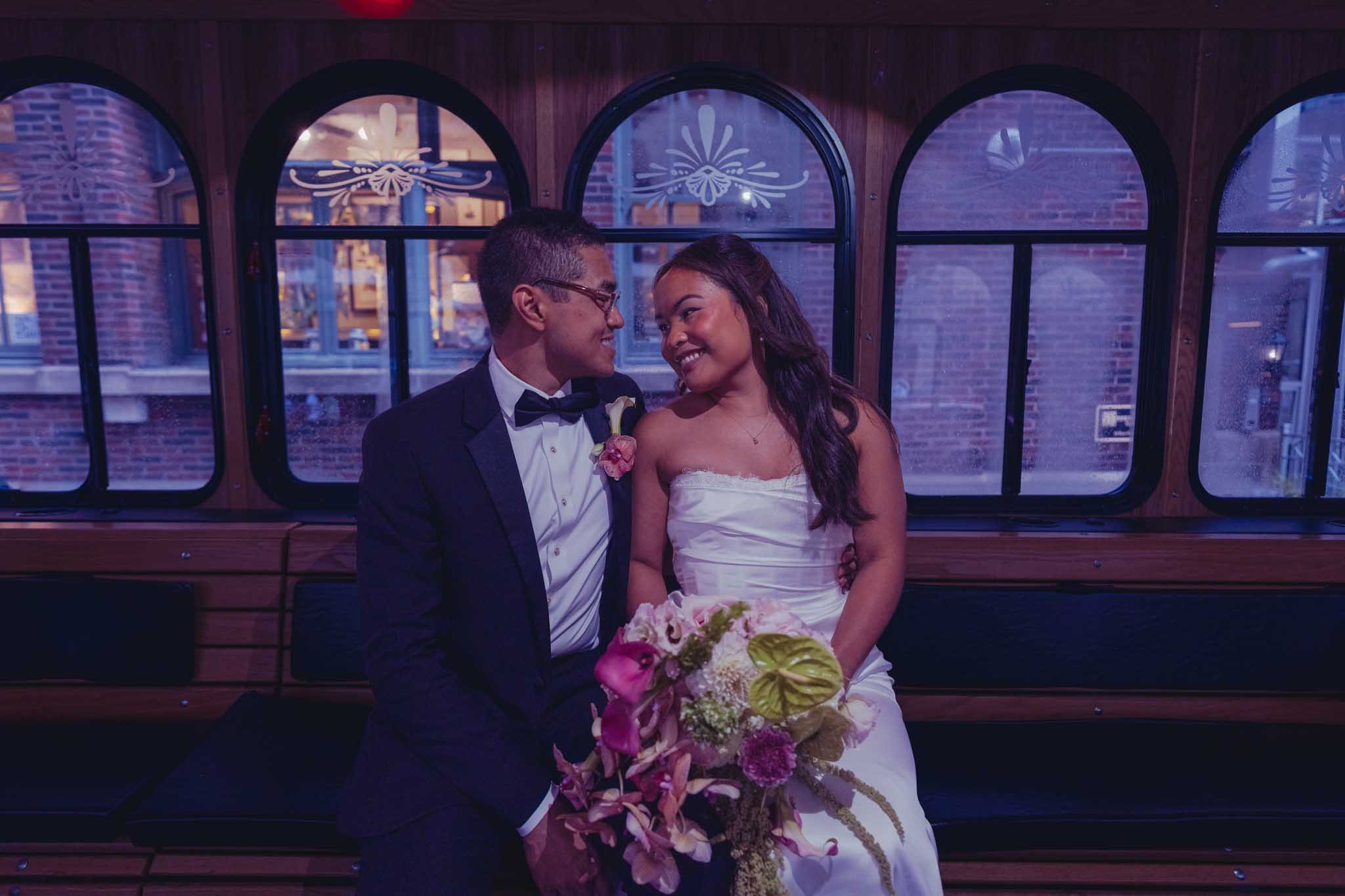 Jason and Alexis laughing together on the wedding trolley, her bouquet in hand