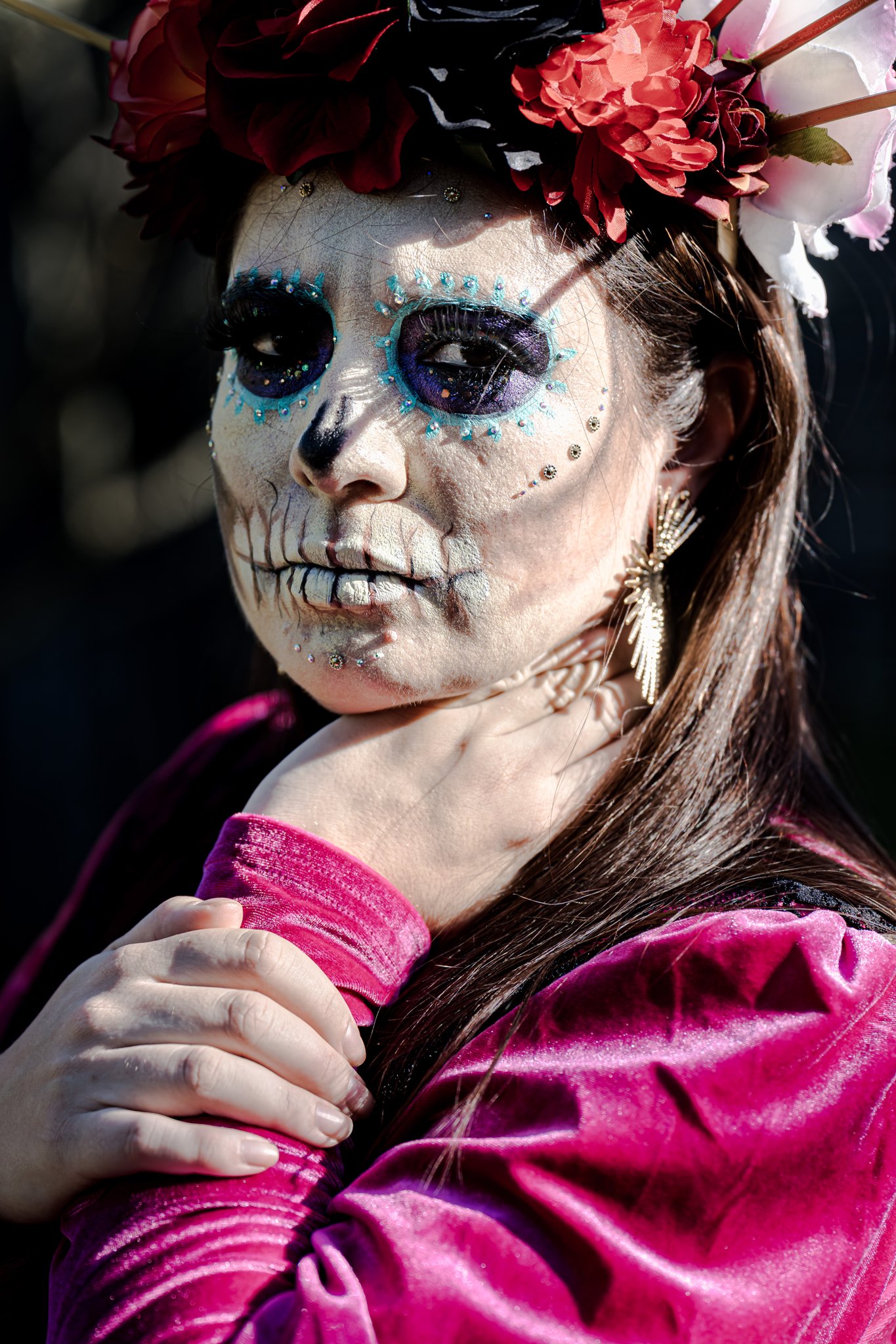 Close portrait of a catrina with skull face paint and a crown of red roses