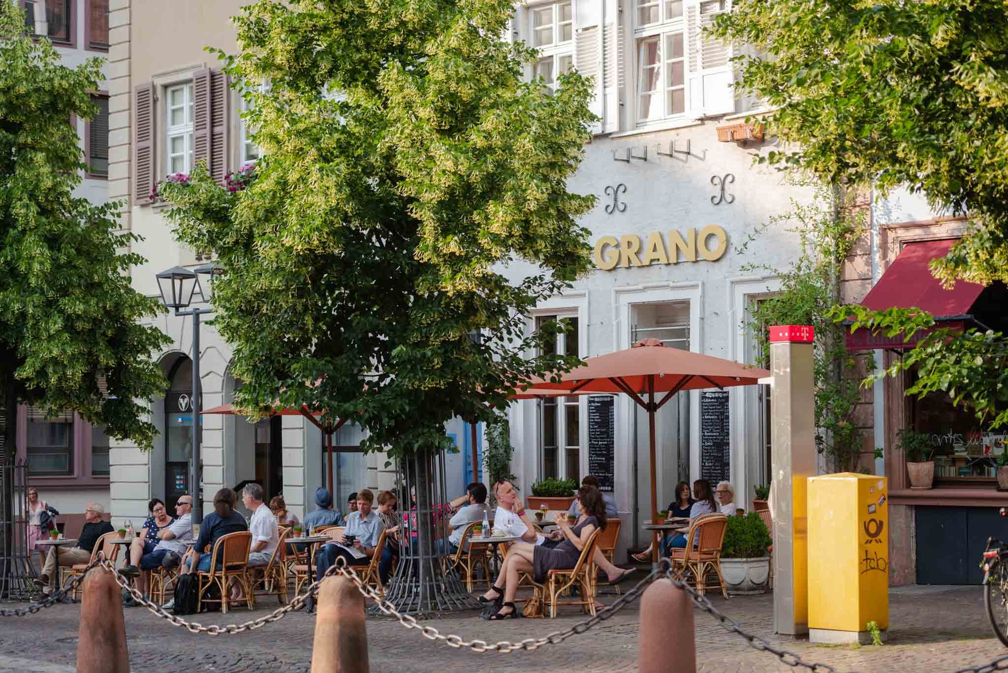 People at café tables under the trees on a Heidelberg square