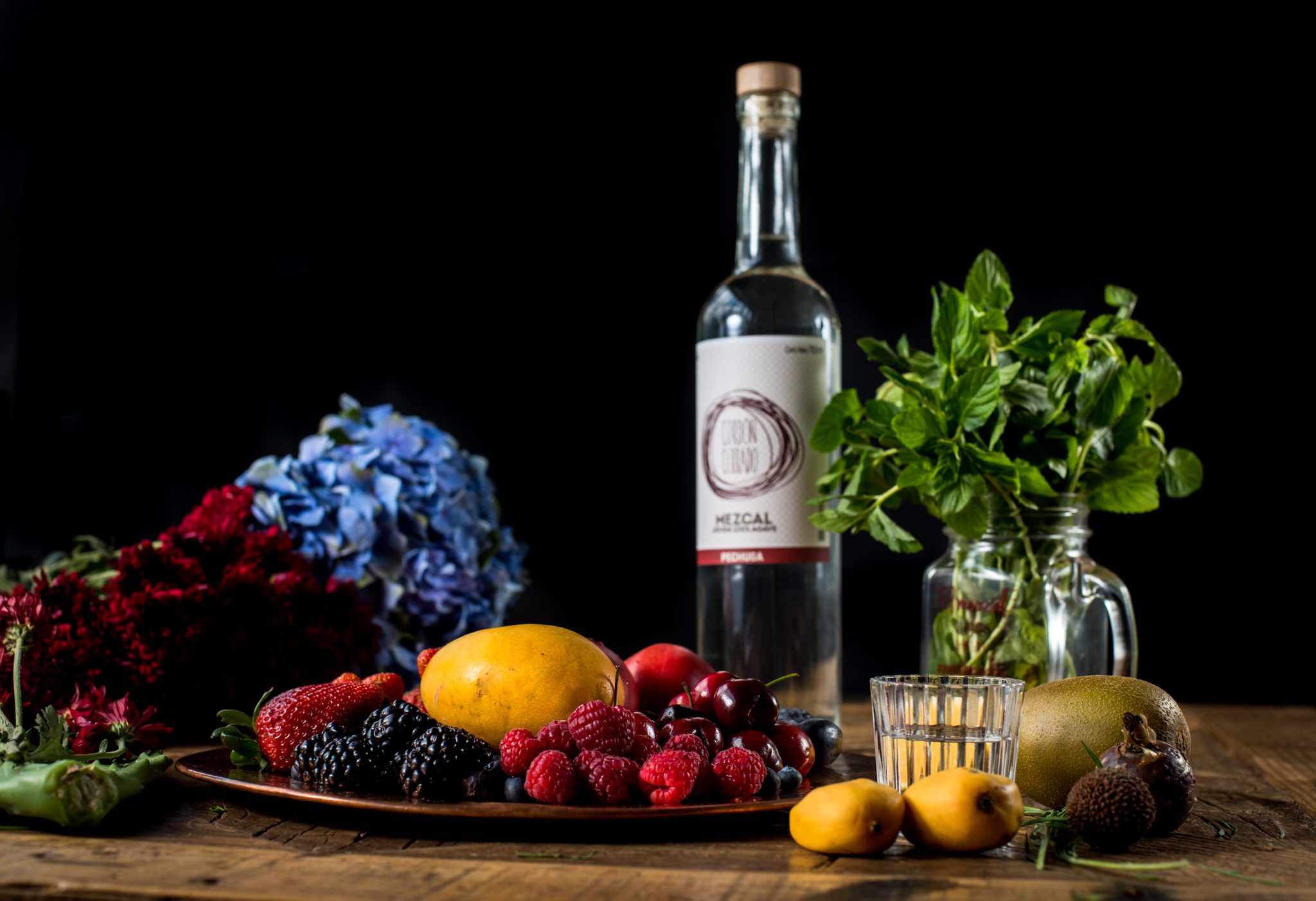 Botella de mezcal con frutas y flores