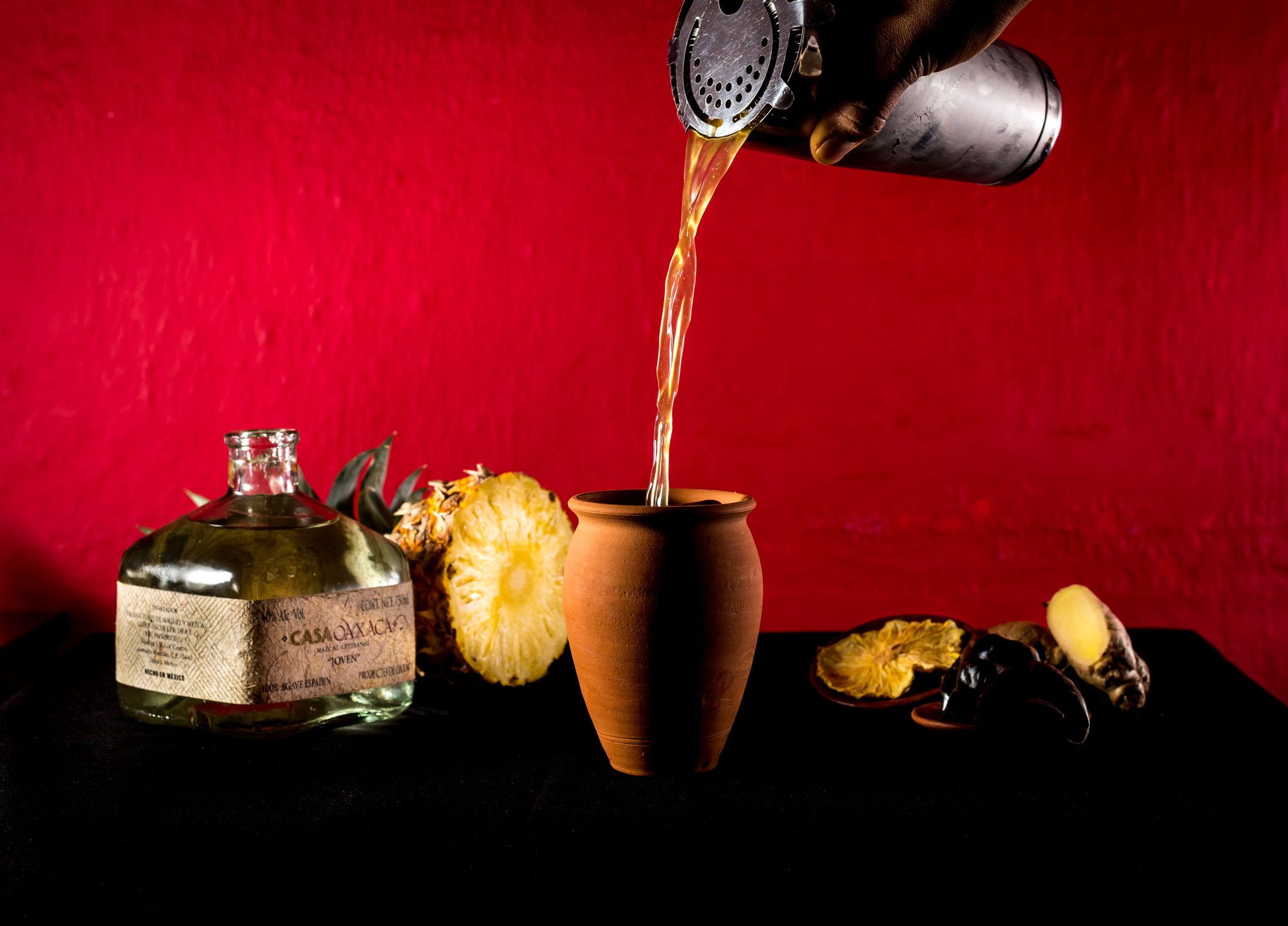 Mezcal servido en jícara sobre fondo rojo