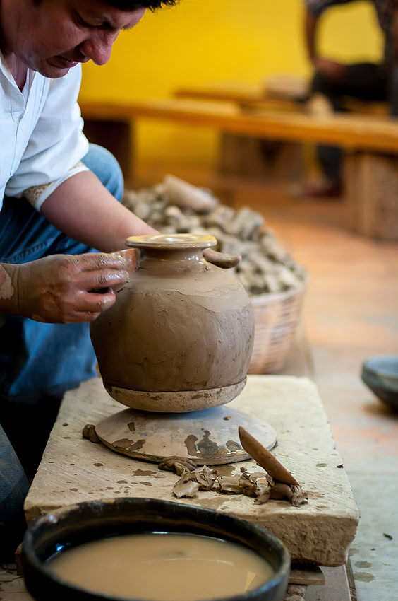 A potter shaping black clay on a hand-turned wheel, Oaxaca