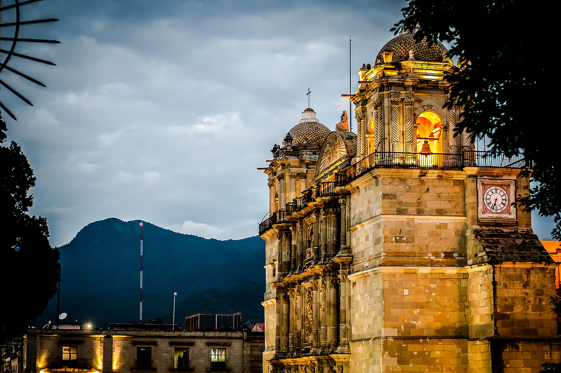 Oaxaca’s cathedral lit gold at dusk with the Sierra Norte behind it