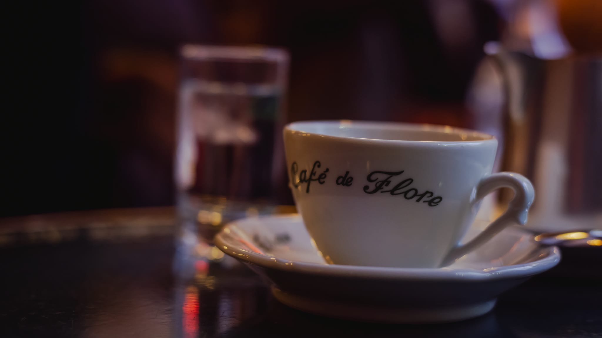 A Café de Flore coffee cup on a dark table