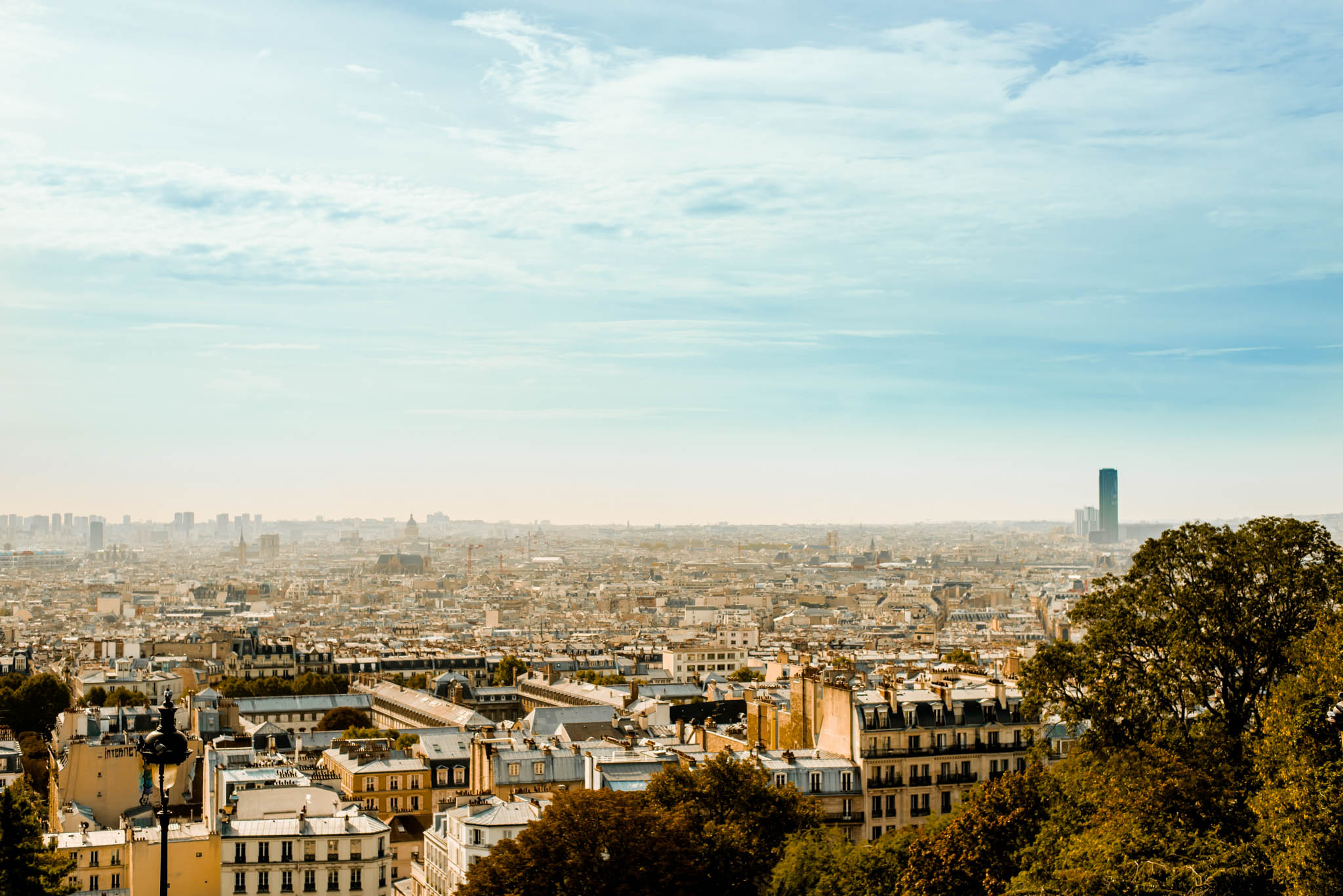 Paris rooftops in hazy afternoon light, seen from Montmartre, with the Montparnasse tower on the horizon