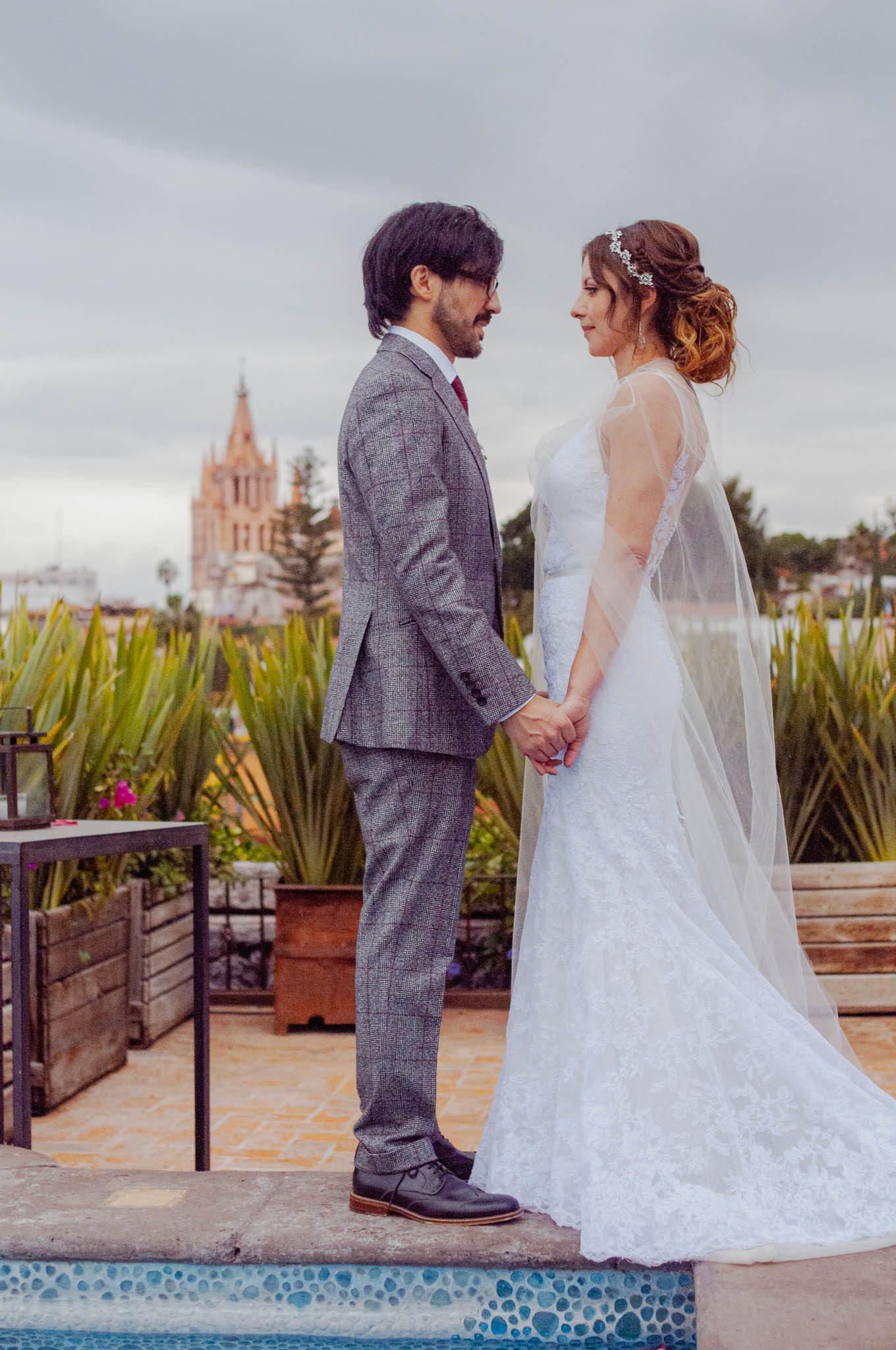Bride and groom holding hands on the Hotel Nena rooftop with the Parroquia in the distance