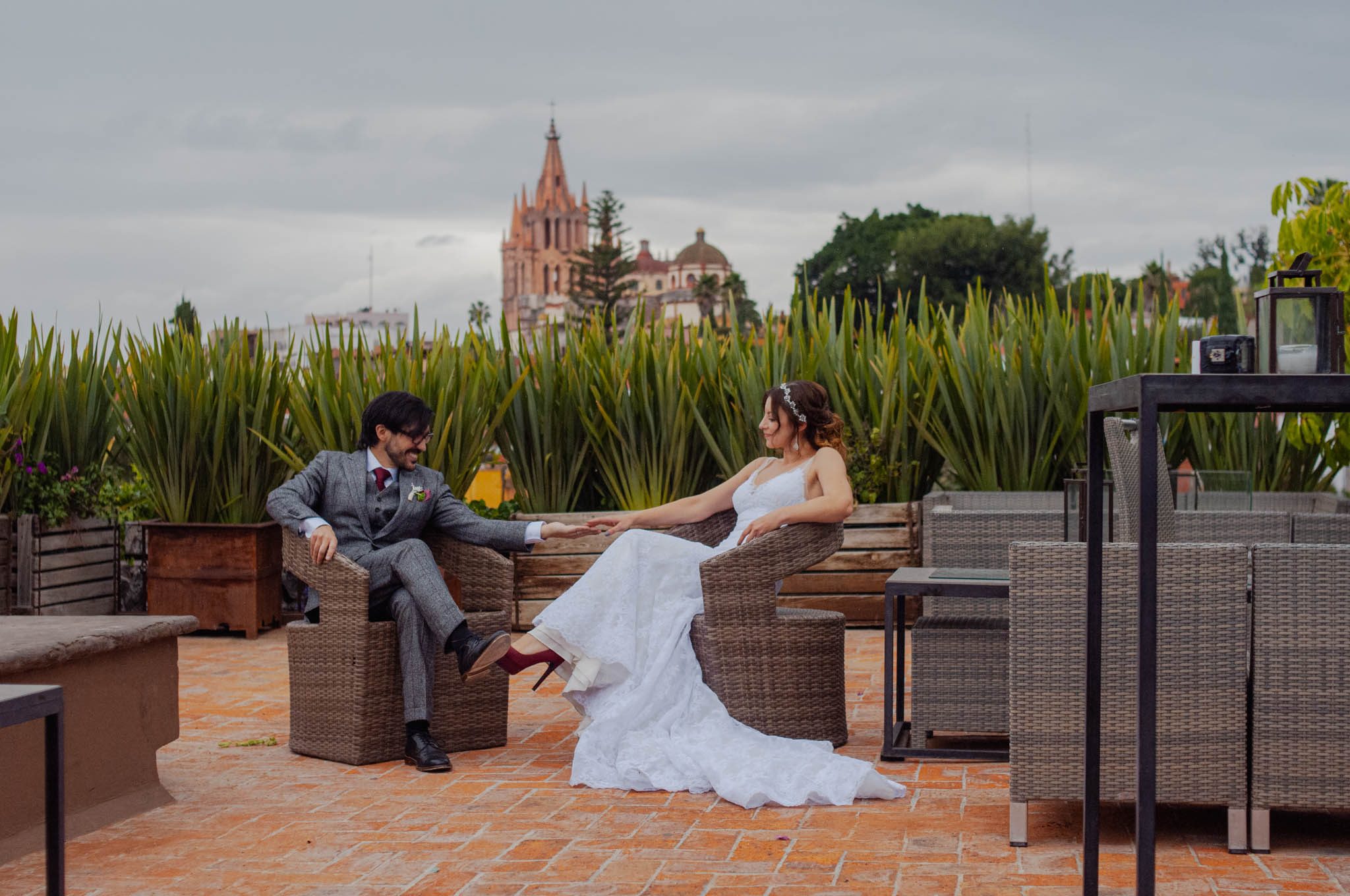 Bride and groom relaxing on the Hotel Nena rooftop, the Parroquia on the skyline
