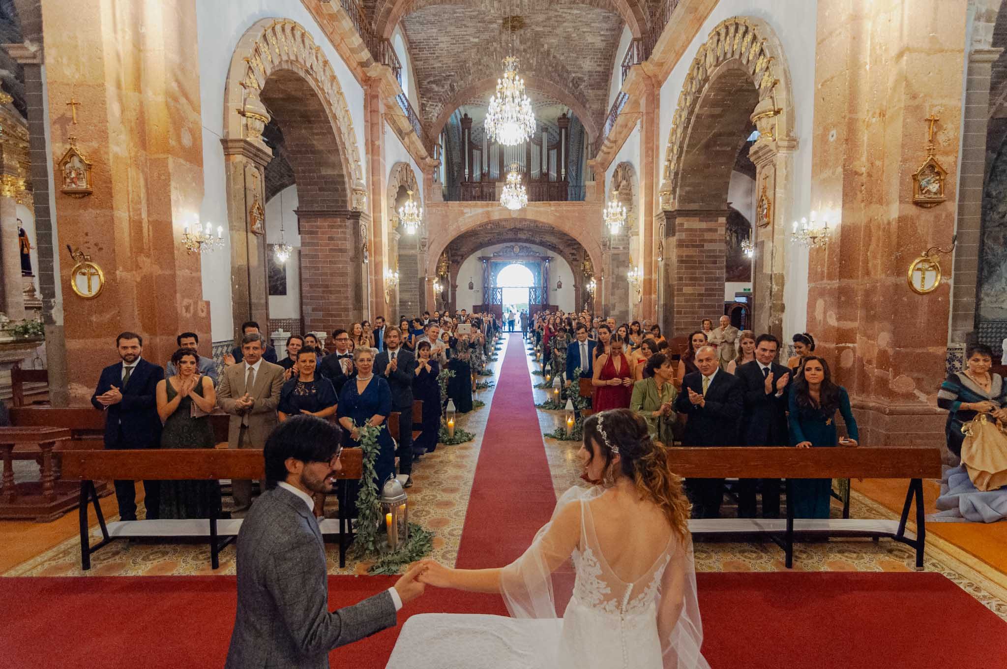Groom taking the bride's hand at the altar, the full church behind them