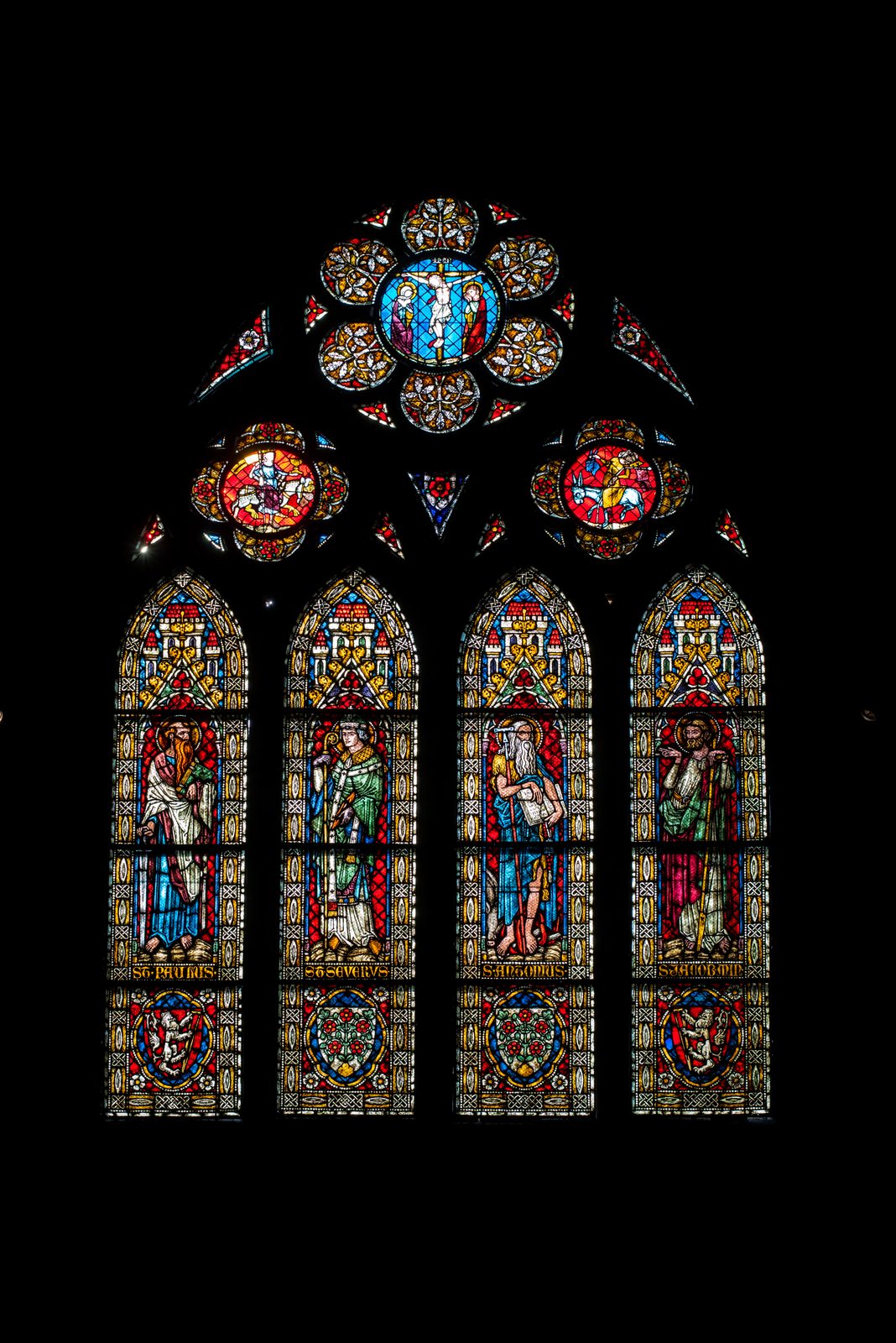 A stained-glass window glowing in the dark inside Freiburg Minster