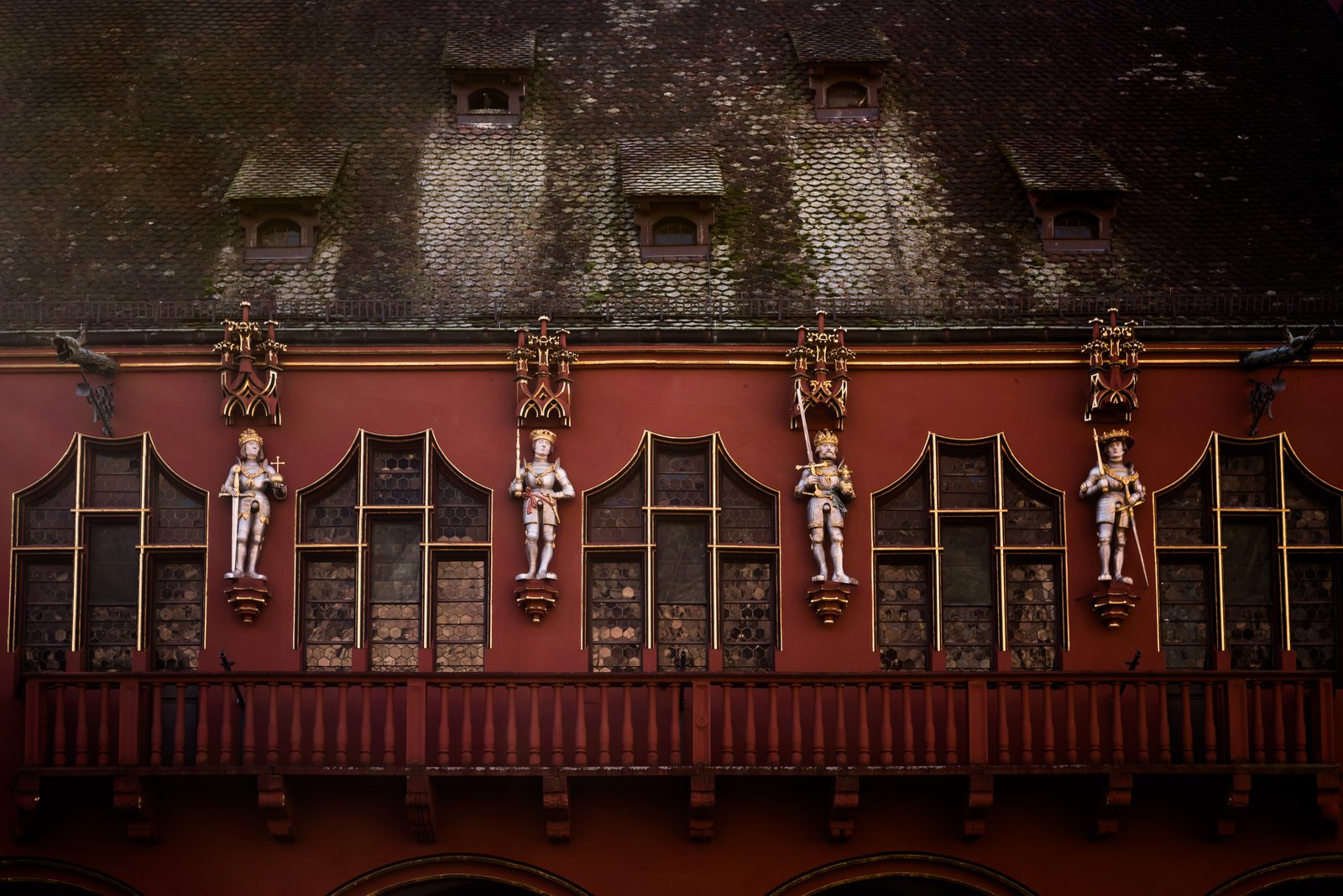 Statues between the windows of the red Historisches Kaufhaus on the Münsterplatz