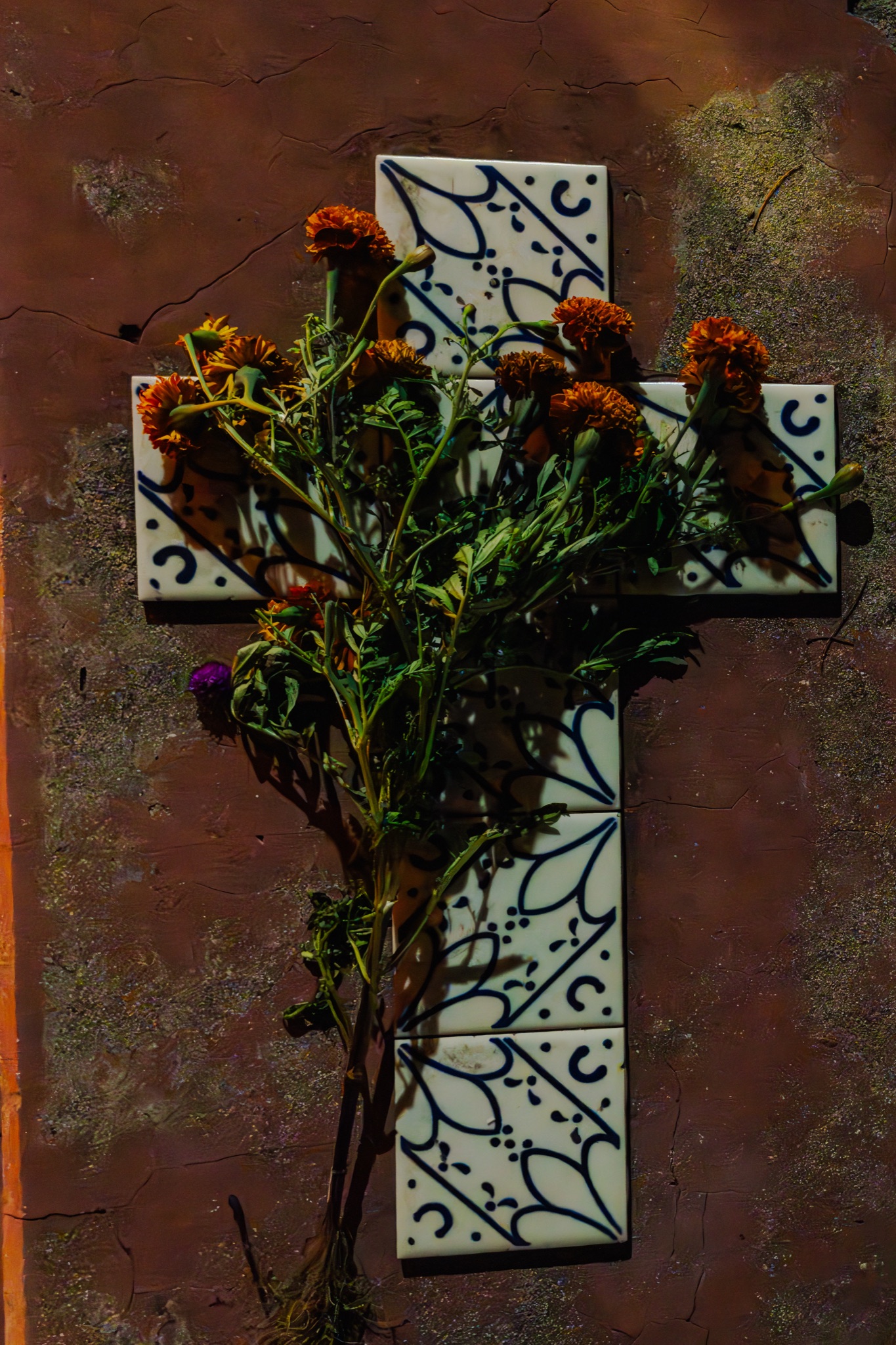 A talavera cross with marigolds in a cemetery in Oaxaca