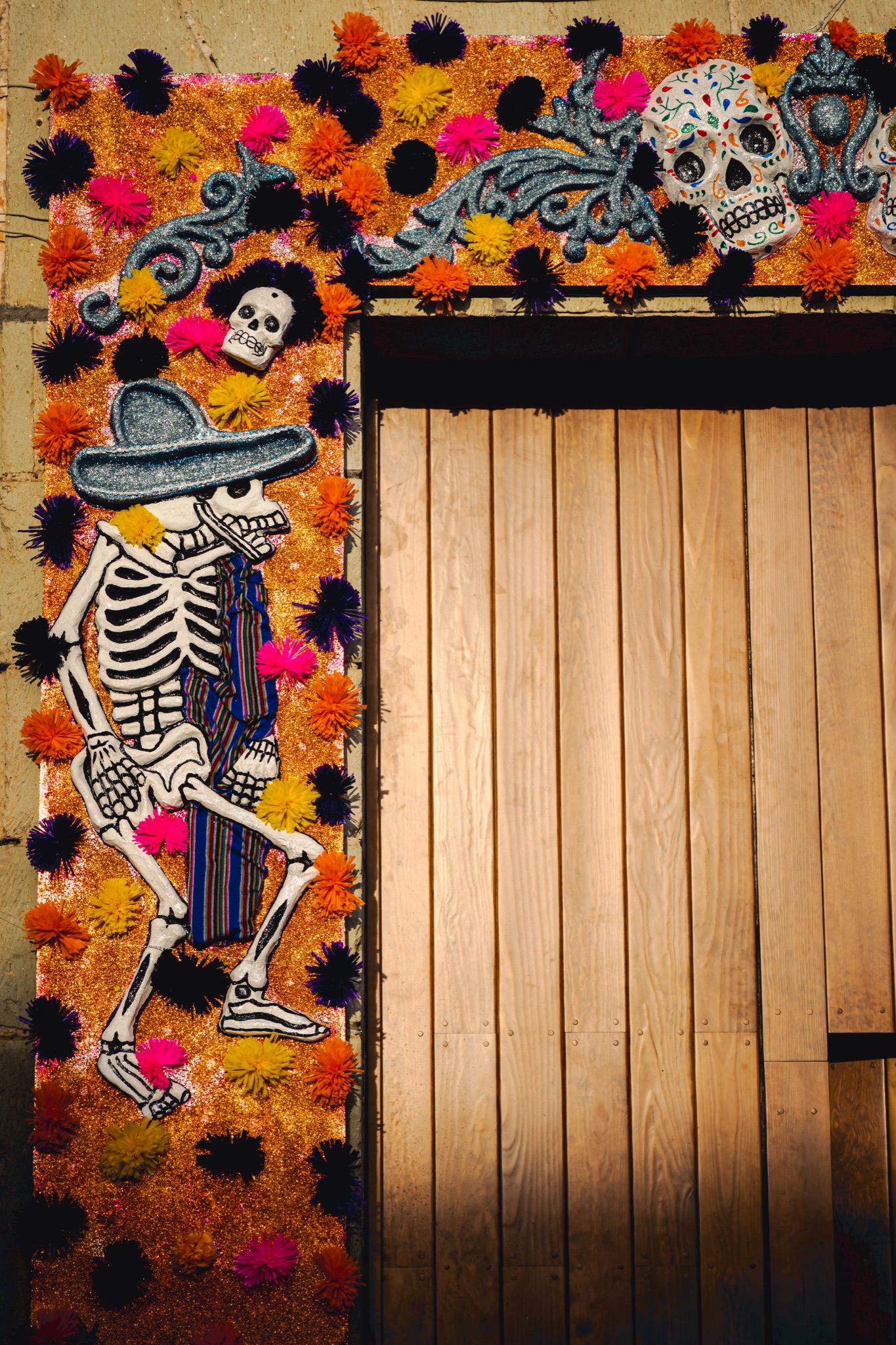 A wooden door framed with marigolds and a painted skeleton in Oaxaca