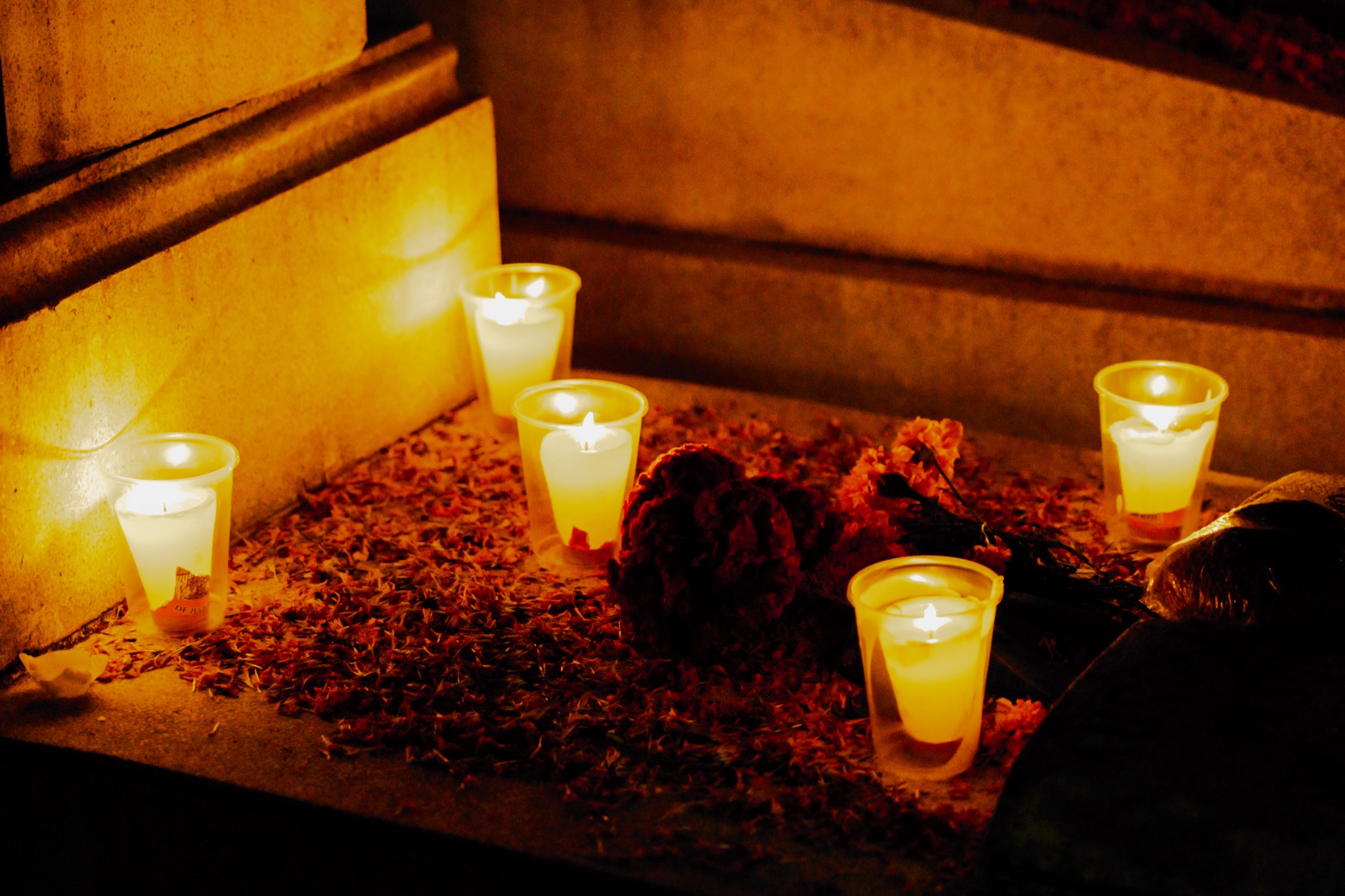 Candles lit on a grave covered in marigold petals