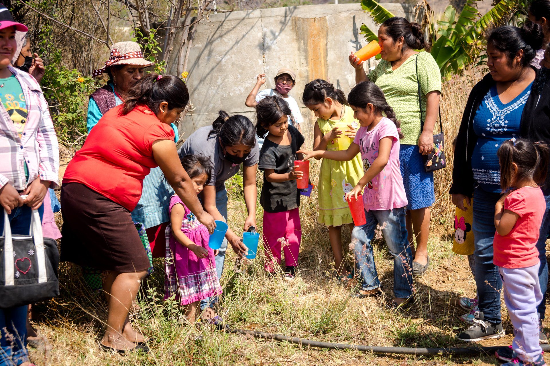 Women handing out cups of water to children