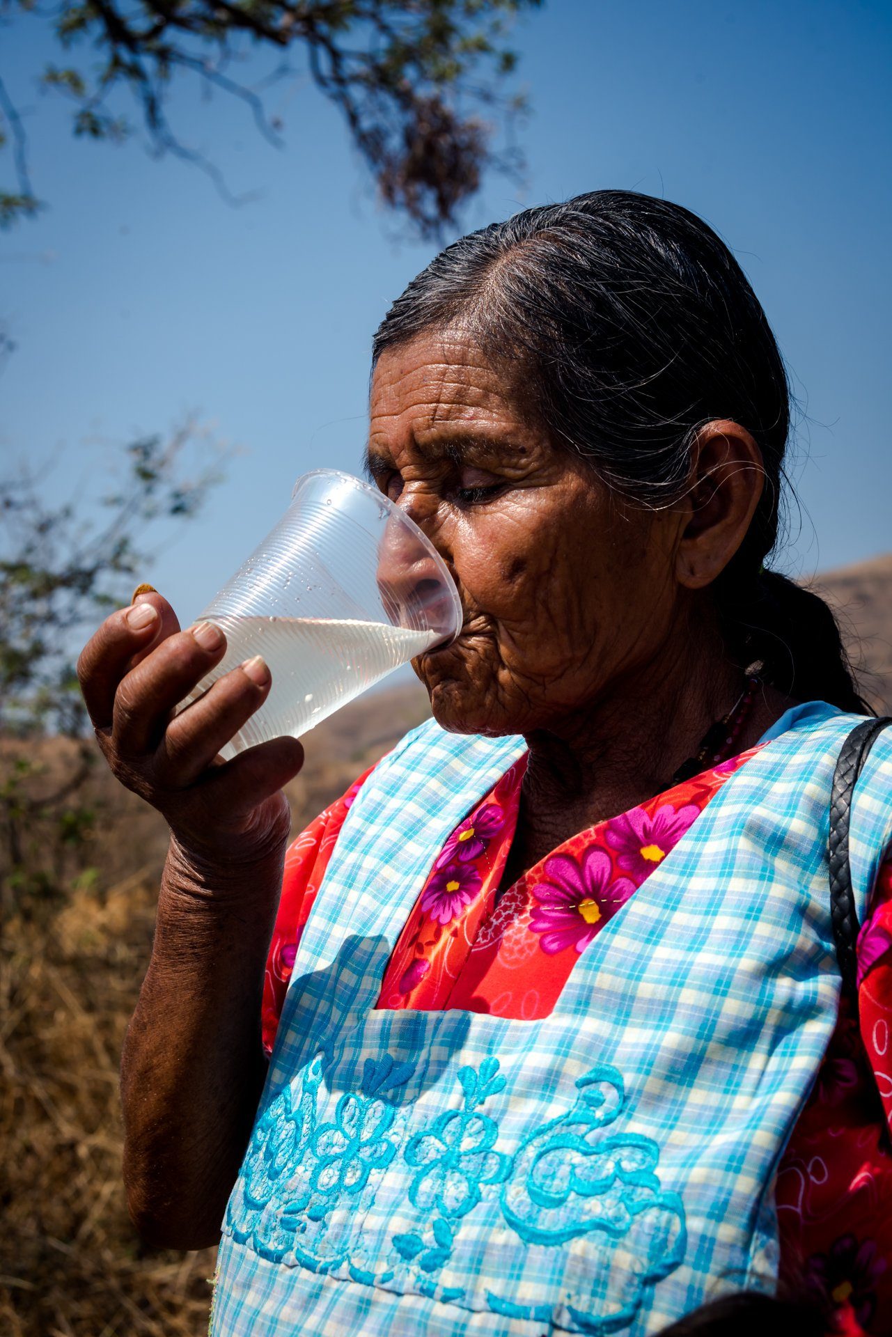 An older woman drinking a glass of water