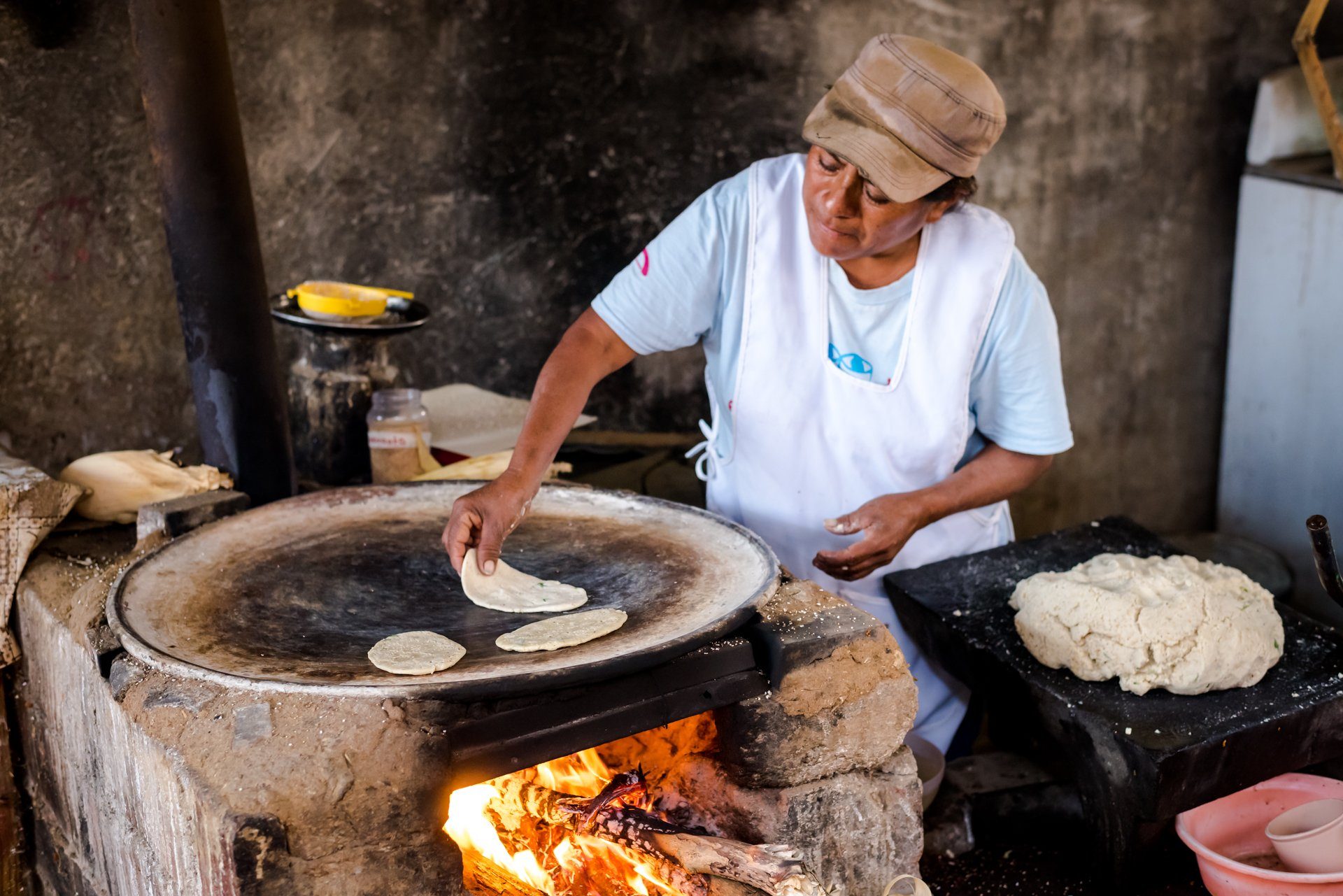 A woman making tortillas on a wood-fired comal