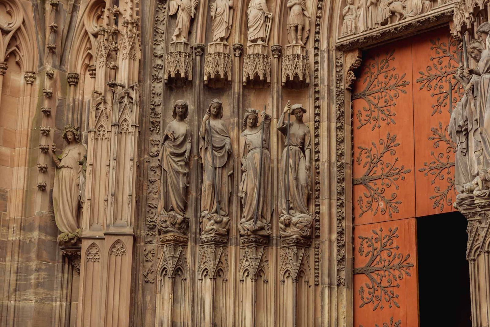 Carved stone figures and a red door on the west front of Strasbourg Cathedral